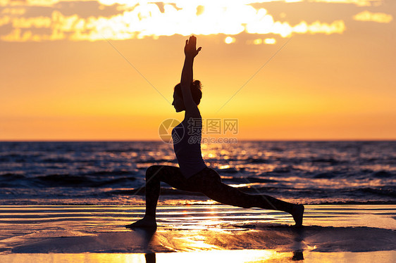日落时海滩上练瑜伽的女人的剪影图片