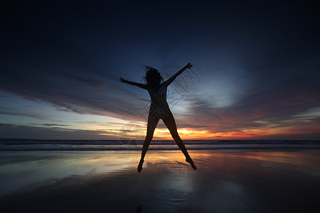 快乐的女人日落时跳海滩上,巴厘岛,塞米尼亚克,双六海滩图片