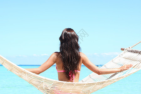 海滩上吊床上的女人个穿着比基尼的女人坐海边的吊床上的后视镜图片