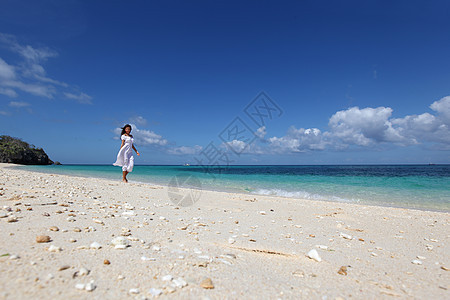 海滩上穿裙子的女人穿着白色连衣裙海滩上散步的漂亮轻女人图片