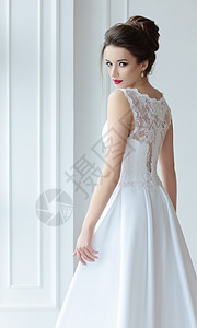 新娘穿着华丽的白色连衣裙站后,看着他的肩膀图片