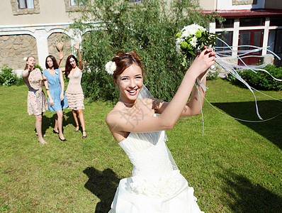 穿着白色婚纱的轻新娘向伴娘扔了花图片