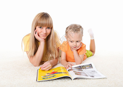 轻的母亲地毯上给她的小女儿读本书图片