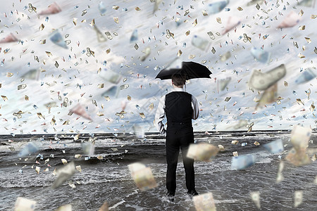 轻的商人金钱雨下着雨伞站着高清图片