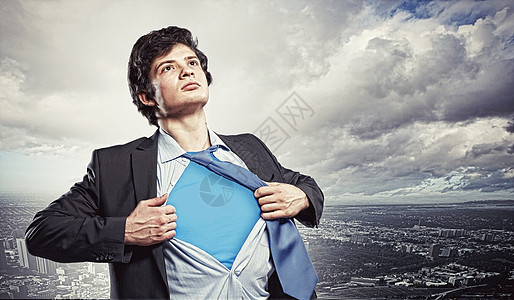 轻的超级英雄商人轻商人的形象,展示超级英雄西装他的衬衫下站城市背景图片