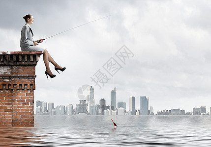 捕鱼的女商人建筑物顶部用棍子钓鱼图片