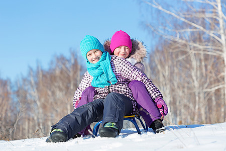 冬天的乐趣两个可爱的女孩美丽的雪冬公园里享受雪橇图片