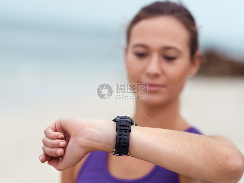 运动的轻女人看着她的手表图片