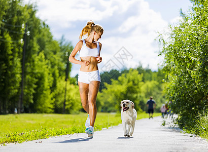 运动女孩轻迷人的运动女孩公园里狗跑步图片