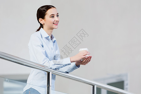 咖啡休息时间随意的白种女人站阳台上,手里着咖啡图片