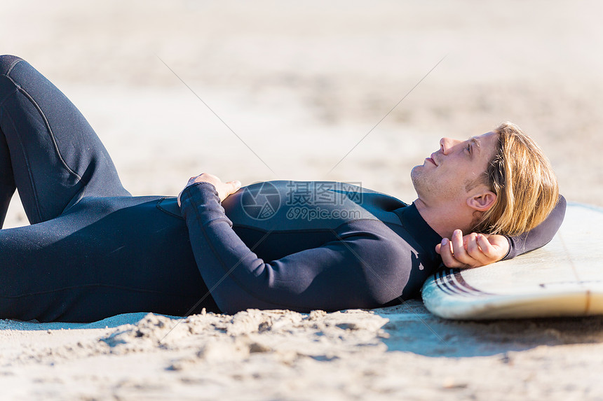 个轻的冲浪者海滩上冲浪需要休息下图片