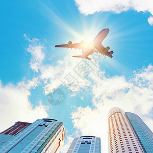 城市上空的飞机飞机飞过摩天大楼的图像底部视图图片