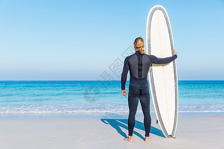 个轻的冲浪者海滩上冲浪等待个完美的波图片