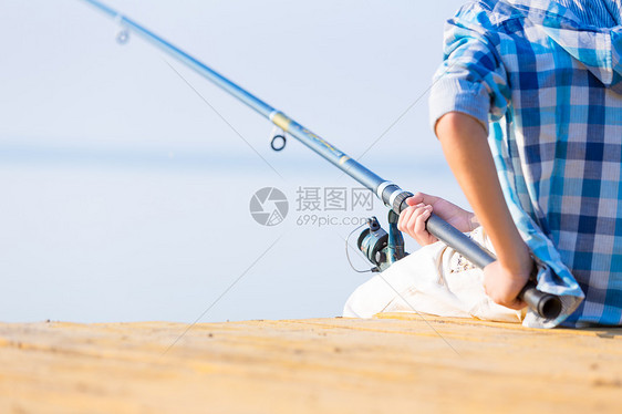 个着鱼竿的男孩的手的特写个男孩的手的特写,他着根钓鱼竿码头上钓鱼图片