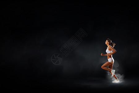 全速前进轻的女运动员黑暗的背景下跑得很快高清图片