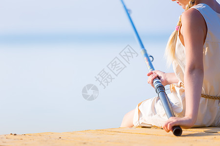 户外钓鱼穿着连衣裙帽子的女孩带着钓鱼竿码头钓鱼背景