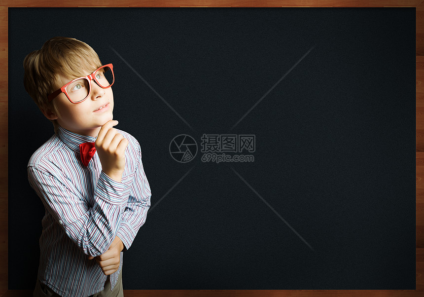 聪明的小学生戴着红色眼镜的聪明男孩靠近黑板,公式图片