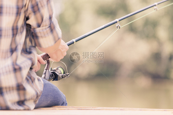 夏天钓鱼戴帽子的轻人坐桥上钓鱼图片