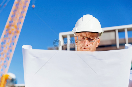 建筑工地的工程师建设者工程师建筑工人施工场景穿着带蓝图的安全背心图片