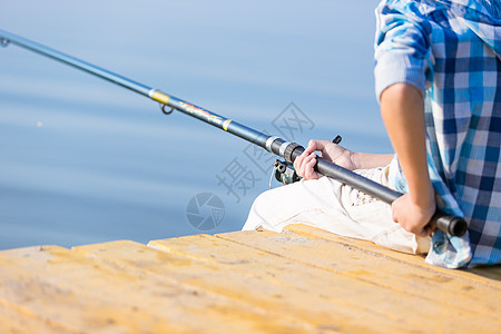 个着鱼竿的男孩的手的特写个男孩的手的特写,他着根钓鱼竿码头上钓鱼图片
