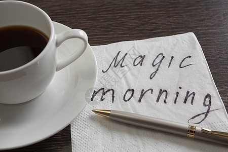 咖啡杯餐巾纸留言神奇的早晨信息写木制桌子上的餐巾纸上图片