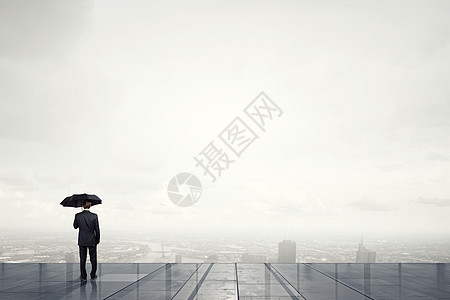 带着黑色雨伞的人带着雨伞的商人的背景看着城市图片