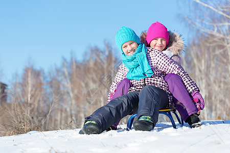 冬天的乐趣两个可爱的女孩美丽的雪冬公园里享受雪橇图片