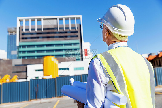 建筑工地的工程师建设者工程师建筑工人施工场景穿着带蓝图的安全背心图片