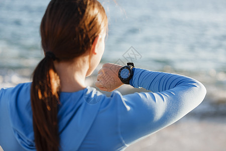 跑步的女人带着心率监视器海滩上跑步轻的跑步女子,心率监测器海滩上跑步图片