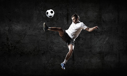 足球运动员足球运动员黑暗背景下踢球图片