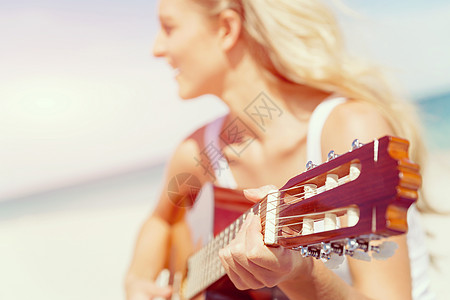 美丽的轻女人海滩上弹吉他美丽的轻微笑的女人海滩上弹吉他图片