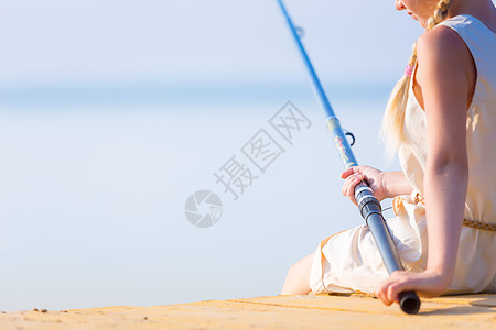 户外钓鱼穿着连衣裙帽子的女孩带着钓鱼竿码头钓鱼背景