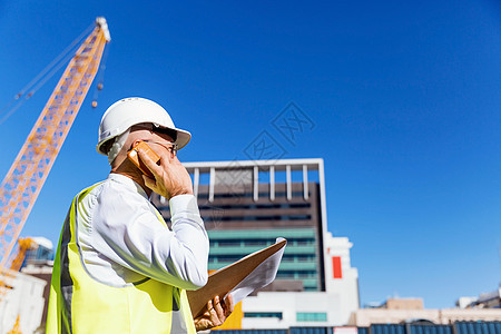 建筑工地的工程师建设者工程师建筑工人施工场景穿着安全背心记事本背景图片