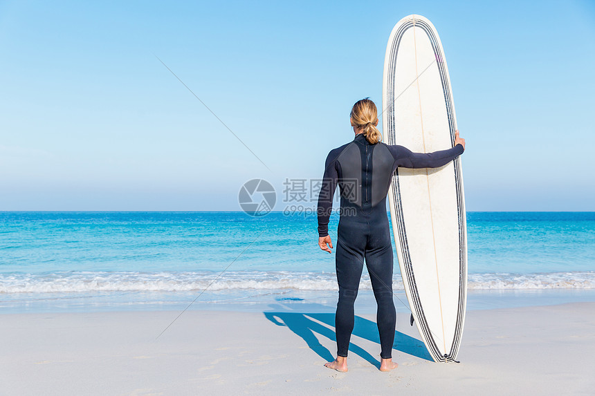 个轻的冲浪者海滩上冲浪等待个完美的波图片