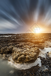 美丽的岩石海滩日落景观长曝光图片
