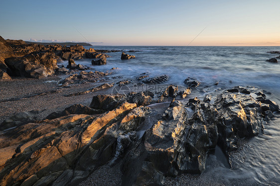 美丽的日落景观图像平静的海洋与岩石海岸线图片