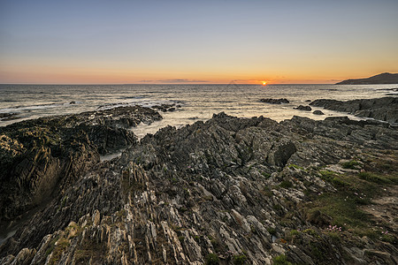 美丽的日落景观图像平静的海洋与岩石海岸线图片