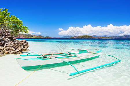 美丽的海滩上用青绿色的水划船图片