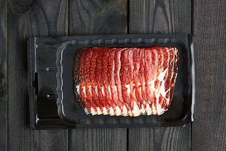 深黑色乡村木制背景上的干猪肉片图片