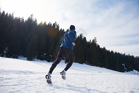 轻人森林里雪地上慢跑,阳光明媚的冬日英俊的运动阿特尔男人跑步图片