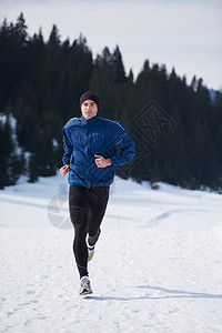 轻人森林里雪地上慢跑,阳光明媚的冬日英俊的运动阿特尔男人跑步图片