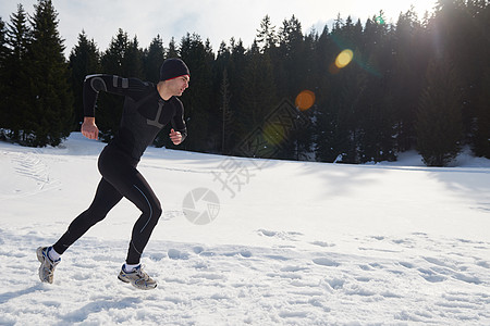 轻人森林里雪地上慢跑,阳光明媚的冬日英俊的运动阿特尔男人跑步图片