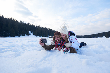 快乐的浪漫情侣新鲜的雪地里玩得开心,自拍与轻人森林中浪漫的冬天场景图片