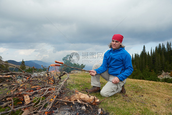 徒步旅行的人山上的篝火上准备美味的香肠图片