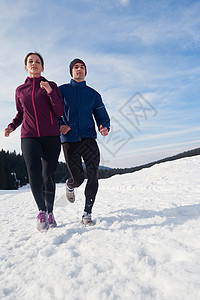 健康的轻夫妇森林里的雪地上慢跑运动员阳光明媚的冬日跑步图片