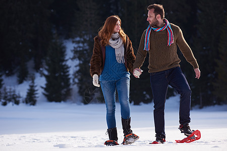快乐的轻夫妇玩得开心,穿着雪鞋散步浪漫的冬季放松场景图片