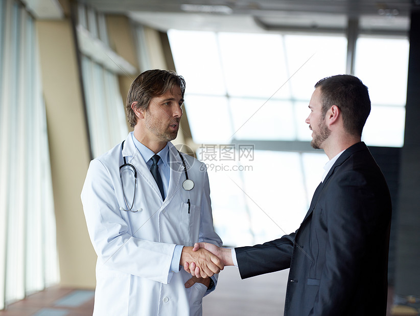 医生医院明亮的现代办公室与病人握手图片