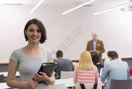 学校课堂上教师教学学生时,快乐女学生手持平板电脑的肖像图片