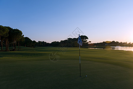高尔夫球边的球场洞代表成就成功的商业理念,美丽的日落背景图片