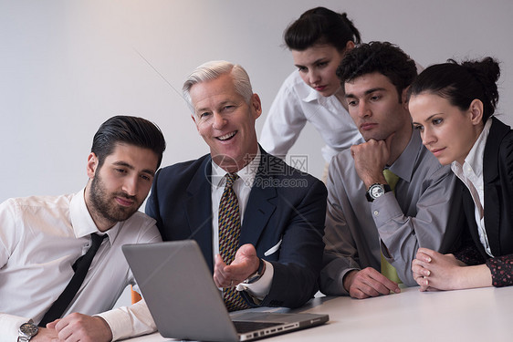 轻的商业人士聚集现代创业办公室与高级经理会长平板电脑笔记本电脑上看演示结果图片